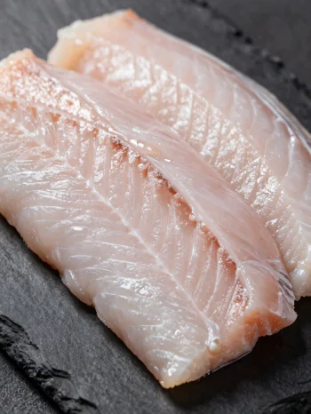 Φρέσκα φιλέτα χελιού με μπαχαρικά σε ξύλινη επιφάνεια κοπής