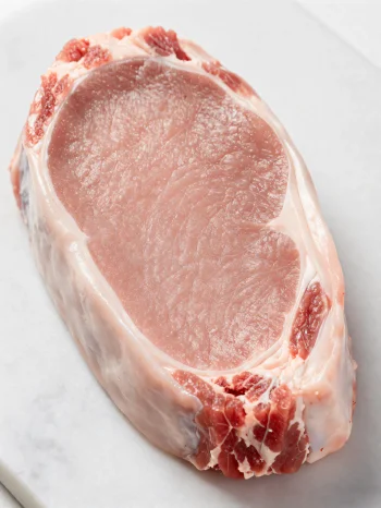 Φρέσκα κομμάτια μόσχου γάλακτος με μπαχαρικά σε ξύλινη επιφάνεια κοπής