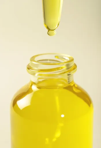 Έλαιο λεμονιού σε μπουκαλάκι και φρέσκα λεμόνια