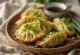 Edamame gyoza κομμάτια με χρυσή βάση σερβιρισμένα με ντιπ σάλτσας σόγιας